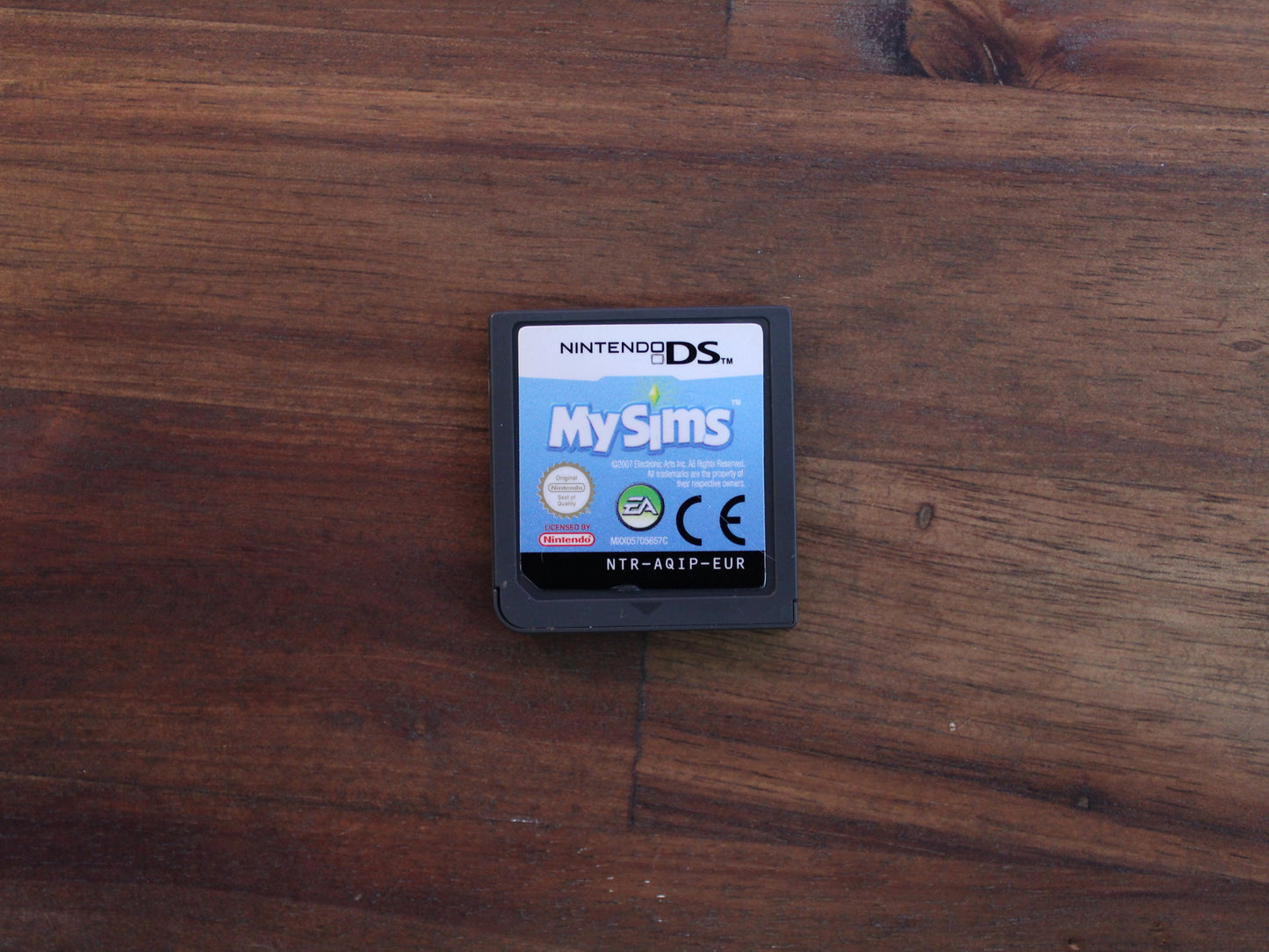 Nintendo DS game cartridge labeled 'MySims' on a wooden surface