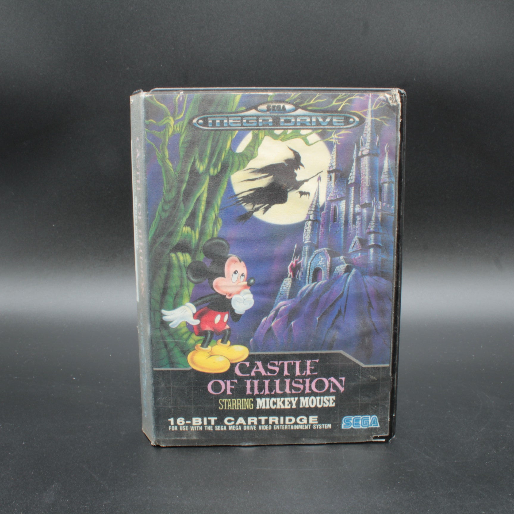 Vintage video game cartridge box for 'Castle of Illusion Starring Mickey Mouse' on a dark background